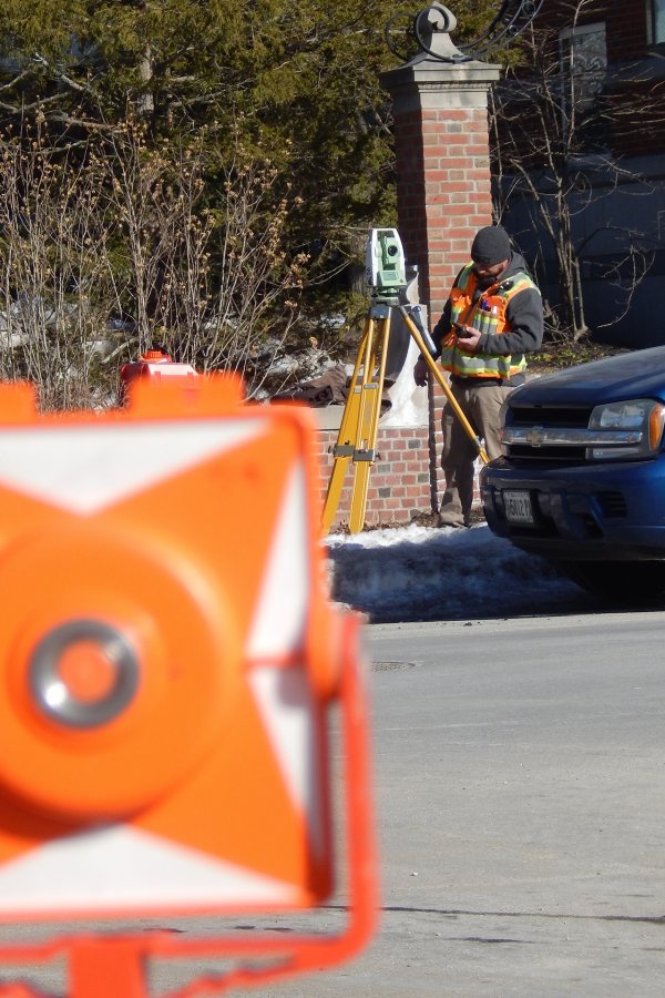 A surveyor at work on Campus Avenue near the Bonney building construction site. (Doug Hubley/Bates College)