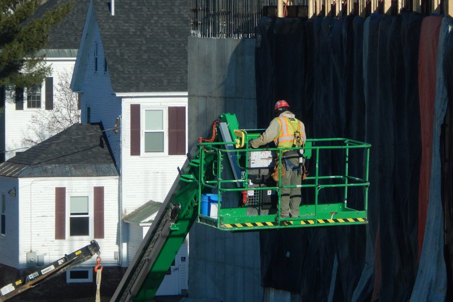 A Consigli Construction employee maneuvers a lift toward the south wall of the Bonney building shortly before a pump starts flowing concrete into the insulated wall forms at right. (Doug Hubley/Bates College)