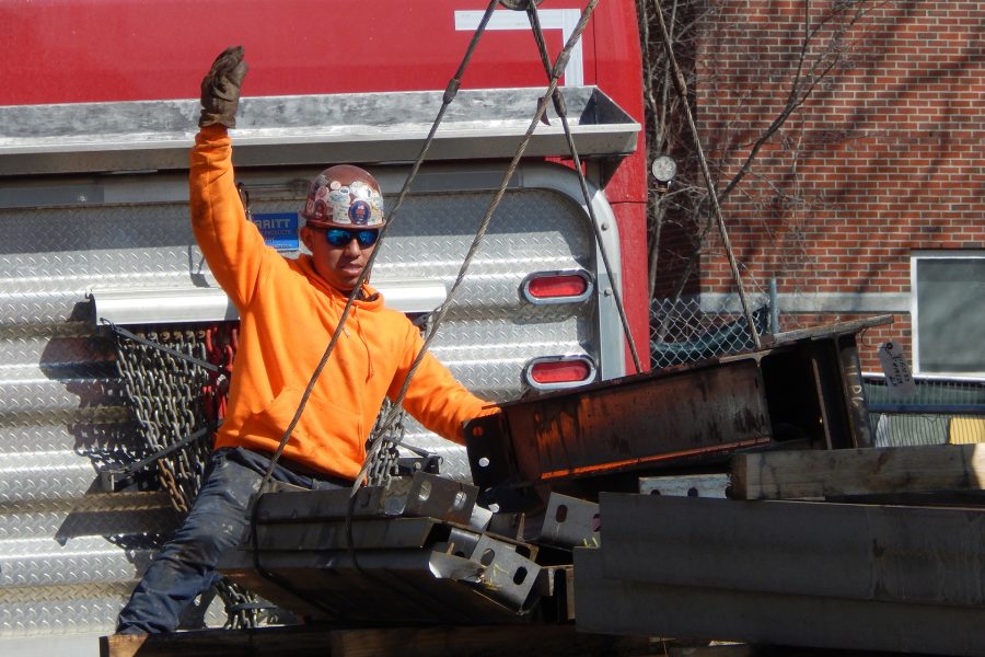 A steelworker gives the signal for the crane operator to hoist a load of components for the Bonney center skeleton on March 3. (Doug Hubley/Bates College)