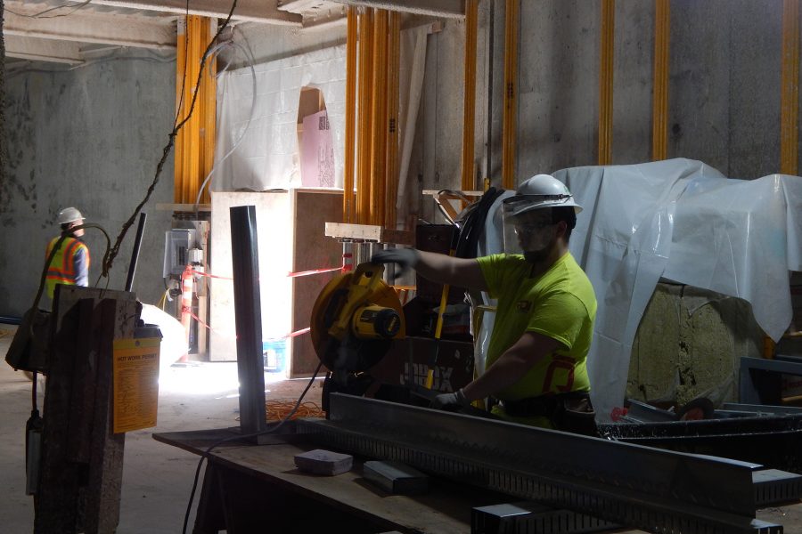 An employee of Roland's Drywall cuts a wall stud in the Bonney building basement. The daylight at left center is entering through an areaway that will be the main air intake for the building. (Doug Hubley/Bates College)
