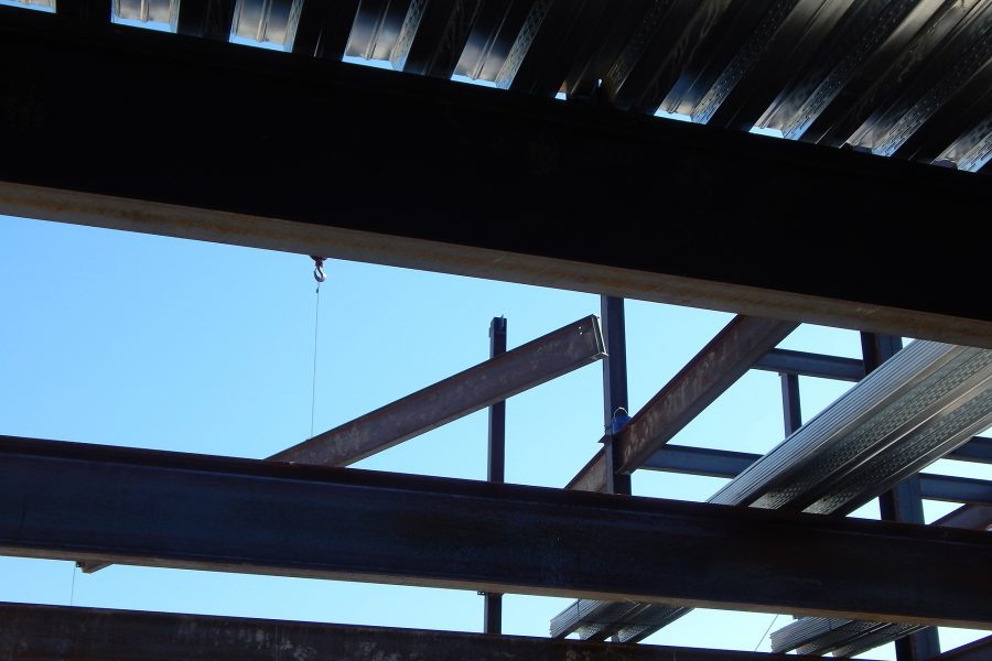 Seen from the Bonney center second floor  through a pattern of third-floor joists, a girder floats in for placement. (Doug Hubley/Bates College)