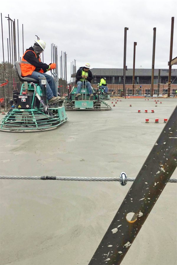 Concrete workers use riding trowels to smooth and condition freshly placed concrete on the third floor of the Bonney Science Center. (Jacob Kendall/Bates College)