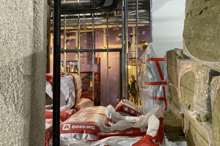 A worker passes insulation stockpiled in the Bonney center basement. (Geoff Swift/Bates College)