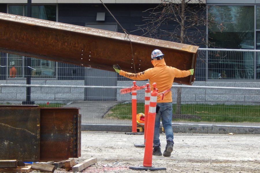 A steelworker guides a beam as the crane lowers it to a staging point on Bardwell Street. (Doug Hubley/Bates College)