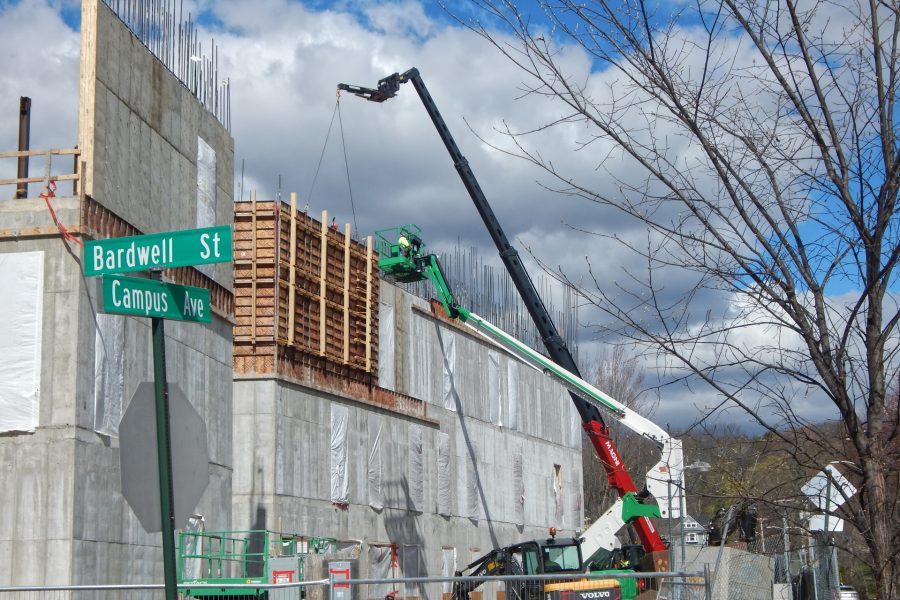 As soon as the white and green manlift makes way, the telescoping-boom crane will peel a section of Symons concrete form off the new third-story wall. (Doug Hubley/Bates    College)