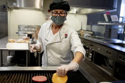 Stacia Poulin, President's House Coordinator/Events AssistantDining, Conferences and Campus Events, prepares a hamburger for Cheryl Lacey on the Commons Grill.Dining Services in CommonsAssociate Professor of Theater Christine McDowell leads a team of Bates students — in residence — as they work in Schaeffer Theatre’s costume shop making coronavirus masks for members of the Bates community. To date, they have provided 340 masks for Dining Services, Security, Facility Services custodians, and Occupational Health and Safety.