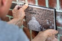 Ron Tardif, mason for facility services, installs the Class of 2020 ivy stone on the front of Pettentill Hall, to the right of the building's entrance.