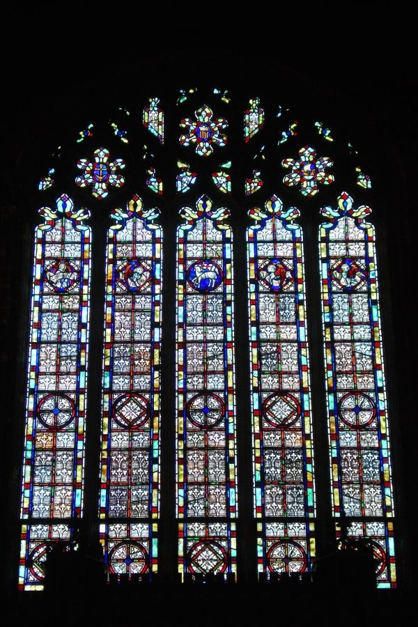 The Gomes Chapel north window in November 2018, prior to restoration. The top row of roundels in this soaring stained-glass installation behind the chapel pulpit depicts, from left, the biblical Matthew, Mark, Christ as the Lamb of God, Luke, and John. (Doug Hubley/Bates College)