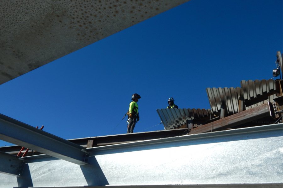 Steelworkers confer atop the roof decking. (Doug Hubley/Bates College)