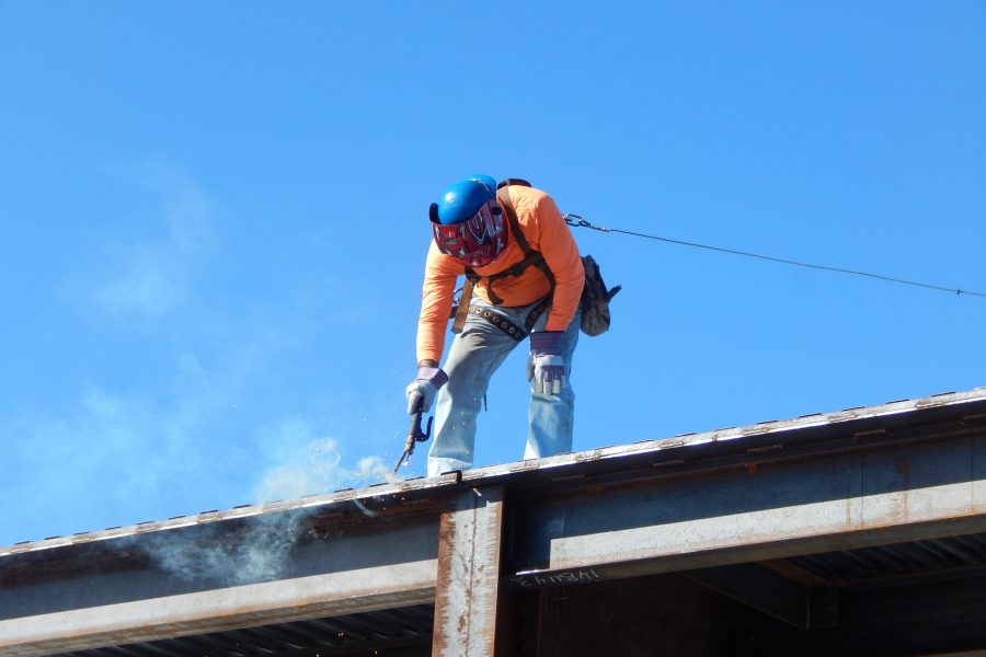 A welder fastens steel roof decking into place on June 8. (Doug Hubley/Bates College)