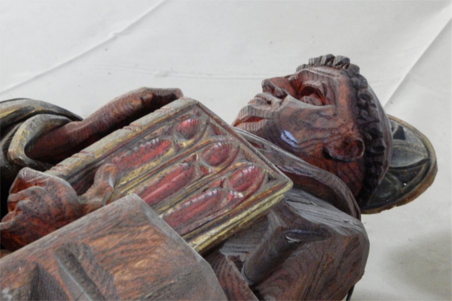 Reclining in the nave while work continues in the chancel, this is one of two wooden statues in Gomes Chapel depicting key figures in the Christian church. (Doug Hubley/Bates College)