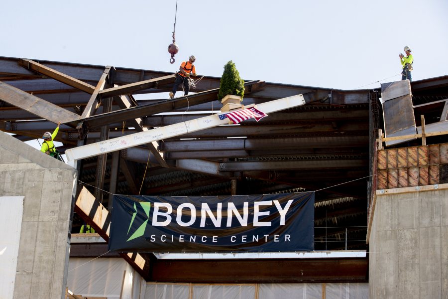 Images from the topping off event on May 16, 2020, at the Bonney Science Center, featuring the final major piece of structural steel being installed on the building. In keeping with tradition, a small spruce tree was attached to the beam fluttered plus a Bates banner and the American flag. The beam has the signatures of Bates participants and members of the Consigli construction crew.Participants: Michael W. Bonney ’80, P’09, P’12, P’15Alison Grott Bonney ’80, P’09, P’12, P’15Sarah R. Pearson ’75, Vice President for College AdvancementA. Clayton Spencer, PresidentChris Streifel, Facilities Services Project ManagerGeoff Swift, Vice President for Finance and Administration and TreasurerPam Wichroski, Director of Capital Planning and ConstructionDave Thomas, Consigli Construction Michael Hinchcliffe, Payette Architecture Firm Bob Schaeffner, Payette Architecture Firm