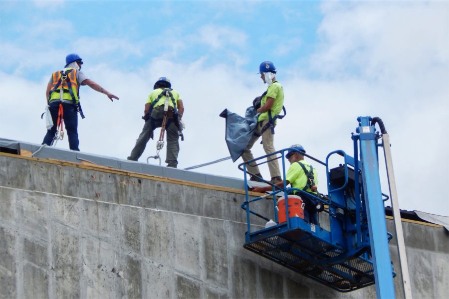 A roofing crew applies a temporary weatherproofing membrane over the Bonney center roof decking. (Doug Hubley/Bates College)