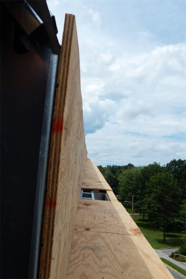 Foreshortened by the camera but extending to the corner of the roof by Nichols Street, this temporary plywood installation gives a sense of where the north-side gutter will run. (Doug Hubley/Bates College)