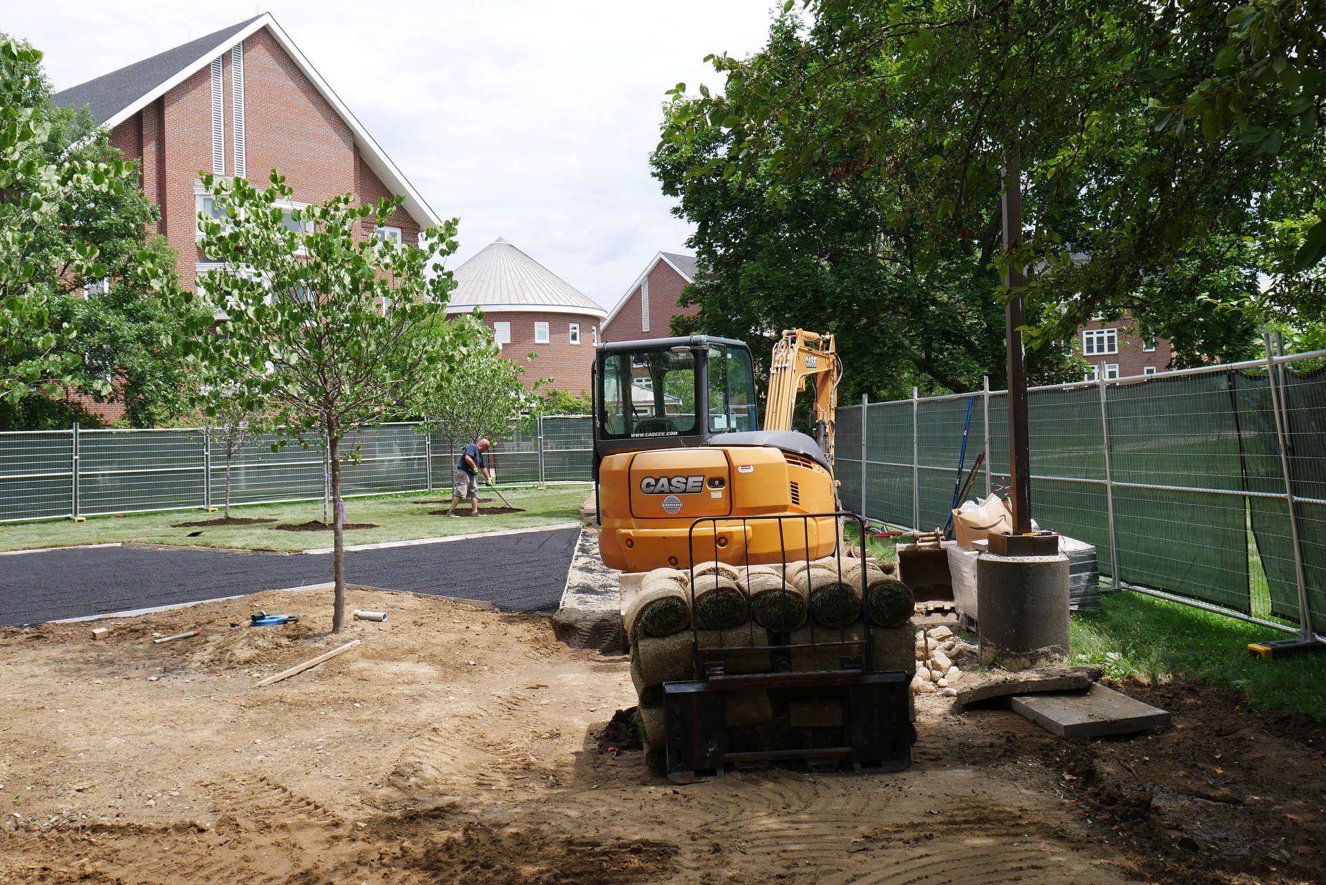 At work on the Veterans Plaza project on July 13. In the background is the Residential Village, and in the foreground is a load of sod rolls. (Doug Hubley/Bates College)