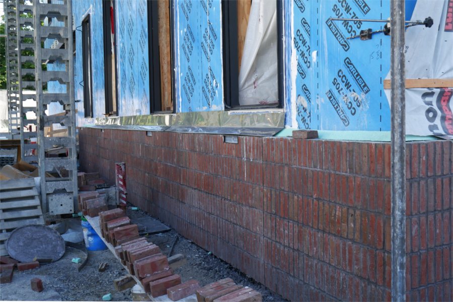 Six "soldier courses" of brick on the Bonney Science Center's Nichols Street wall on Aug. 19. The sheet metal is through-wall flashing that will minimize moisture damage to the brick, and the small rectangles beneath the flashing are light fixtures. (Doug Hubley for Bates College)