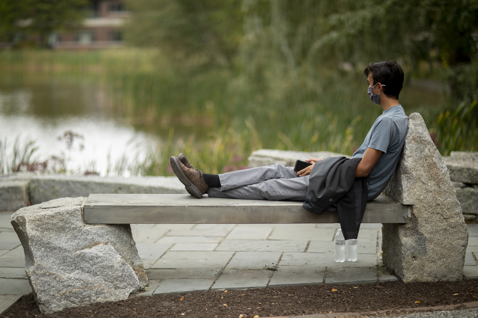 Cameron Frary '24 of Andover, Mass., gazes out over Lake Andrews after finishing his lunch. This bench is one of his two favorite places, the other also adjacent to the Puddle. Frary is a new member of the Bates sailing club, so he's drawn to a water environment.