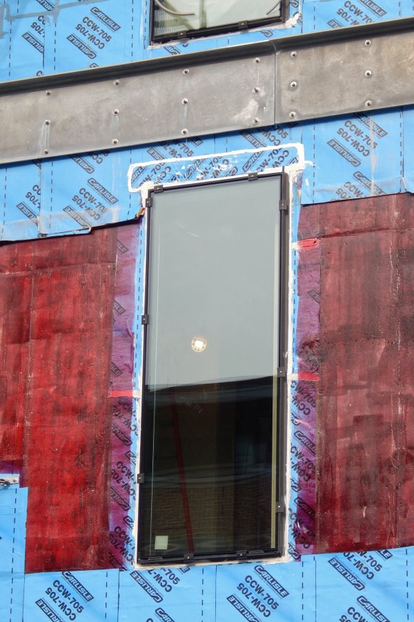 New window glass in the Bardwell Street wall of the science center is surrounded by blueskin moisture barrier and burgundy-colored undercoating. (Doug Hubley/Bates College)