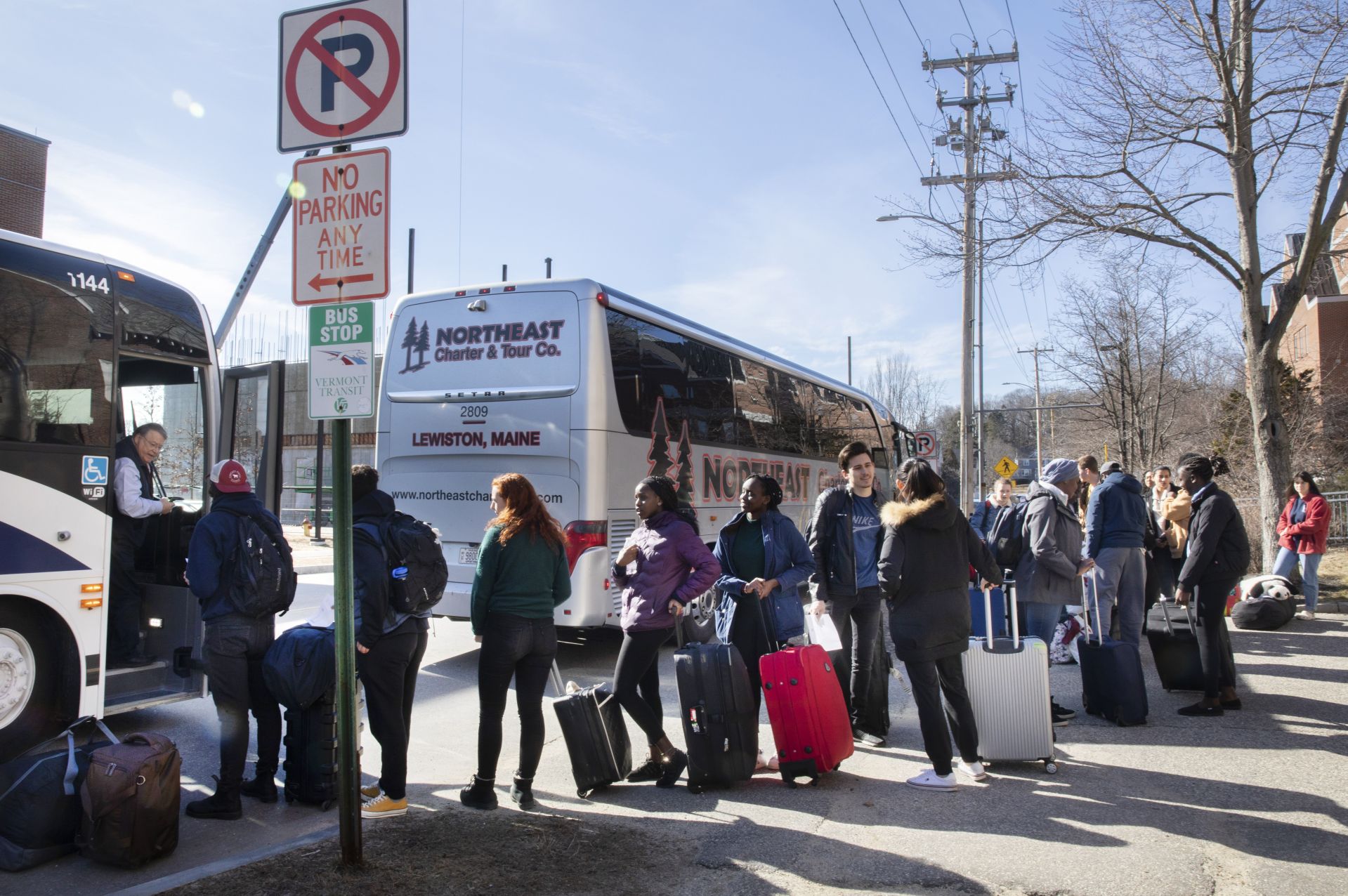 Students gather in front of Chase Hall to take two buses that will take them on the first leg of their trips home. One is a Concord Trailways bus, regularly scheduled daily for 3:30 p.m. pickup. The other is a bus chartered by the College.