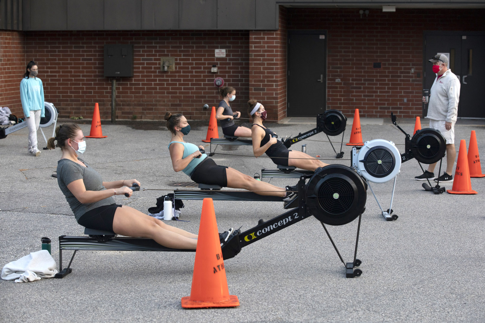 Women's rowing practice with Peter Steenstra and the erg machines behind Merrill Gym on Sept. 17, 2020.

Athlete in black with headband: Eliza Fischer '21 of Chicago,

Athlete with gray t-shirt and pony tail:
 and Eloise Botka '23 of Cambridge, Mass.