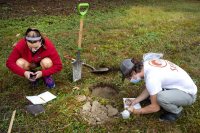 Zoe Knauss '23 of Buffalo, N.Y., who will declare as an ES major, and ES major Sam Gilman '22 of Mendham, N.J., , dig for soil in a field.Prof of Environmental Studies and Christian A. Johnson Prof of Interdisc Studies Holly Ewing and Lecturer in Environmental Studies & Learning Associate in Environmental Studies Camille Parrish take students in the Soils/Lab course for a field trip to Pettengill Farm in Freeport, Maine. A nineteenth century salt-water farm on the estuary of the Harraseeket River, the farm is owned by Freeport Historical Society(FHS). It includes a saltbox house (ca. 1800) on 140 acres of fields, woods, antique apple orchards and salt marsh. Most interesting are the etchings (sgraffitti) found on the plaster walls in the upper chambers of ships, sea monsters, longboats and animals. The farmhouse remains without plumbing, central heat and electricity and is listed in the National Register of Historic Places. Mildred Pettengill was its last resident and lived in the house until 1970.The students are digging up soil and making observations (soil profiles) before putting it back where it came from.ENVR 310 - Soils/LabDepending on one's point of view, soils are geological units, ecosystems, the foundation of plant life, a place for microbes to live, building material, or just dirt. This course takes a scientific perspective and explores the genesis of soils, their distribution and characteristics, and their interaction with plants. Field studies emphasize description of soils, inferences about soil formation, and placement within a landscape context. Labs investigate the chemistry of soils and their role in forestry and agriculture.