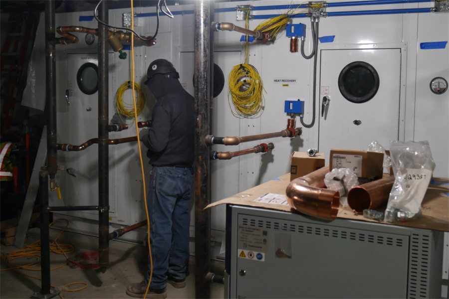 A pipefitter for Warren Mechanical makes connections to one of three air handlers in the Bonney center basement. Smallest of the three, this machine will serve the vivarium while the other two ventilate the remainder of the building. (Doug Hubley/Bates College)