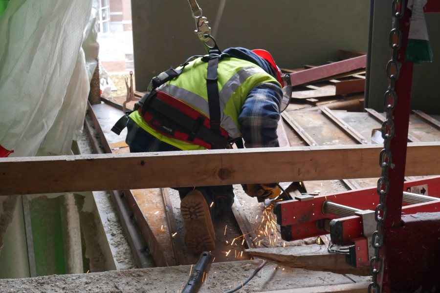 Shown on the third floor of the science center, a steelworker is using a grinder to fit a component of the Monumental Stairs. (Doug Hubley/Bates College)