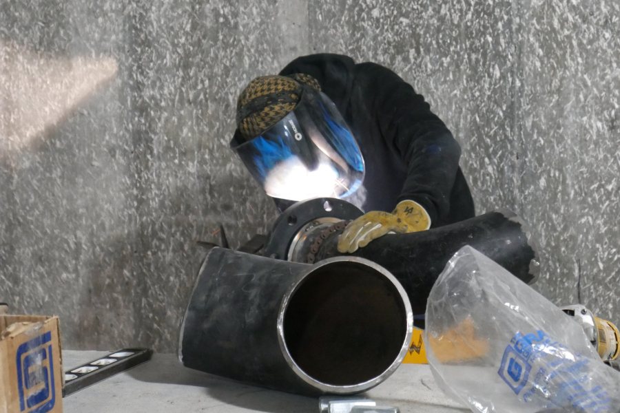 Shown in the Bonney center penthouse, a welder prepares a section of stormwater drainpipe for joining. (Doug Hubley/Bates College)