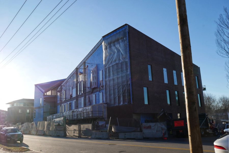 A northwestern view of the Bonney center with the sun rising at left. The "tent"  above the site fence tells you that bricklaying has begun on the Campus Avenue face of the building: This poly enclosure will help keep mortar warm enough to cure properly. (Doug Hubley/Bates College)