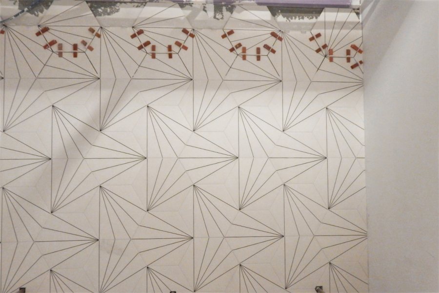 The design of these new tiles in a Bonney center bathroom has some fun with geometry. The red items at the top are spacers that maintain the specified gap between tiles until grout is applied. (Doug Hubley/Bates College)