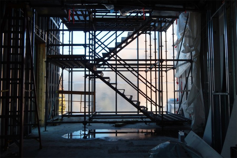 Metal staging, window framing, and wall studs form a complex grid against a backdrop of translucent plastic in the Bonney Science Center's Beacon. (Doug Hubley/Bates College)