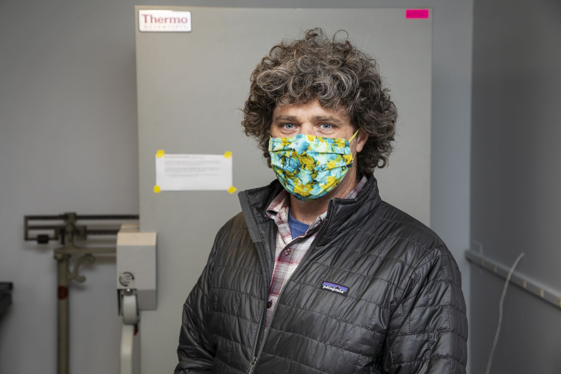 Brett A. Huggett, associate professor biology, poses next to a Thermo Scientific freezer seen inside Carnegie Science Hall at Bates College on December 15, 2020.