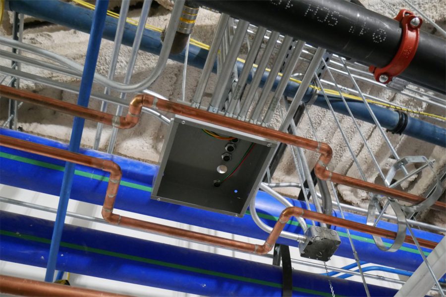 Don't block the box: Along the ceiling of the Bonney Center penthouse, plumbers routed two copper pipes so as to maintain access to the gray electrical junction box at center. (Doug Hubley/Bates College)