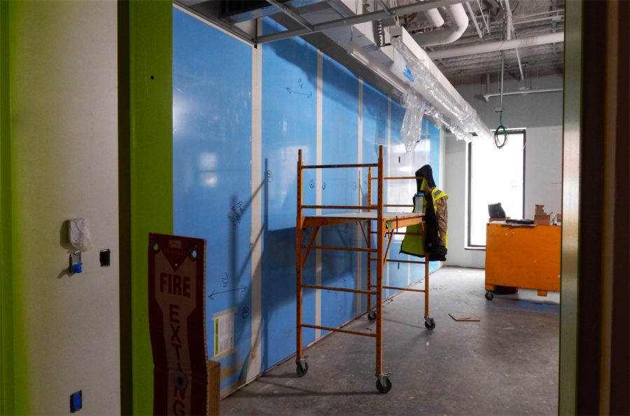 A view into a first-floor Bonney Center classroom. The blue membrane protects dry-erase whiteboards. This room will serve as a shared office for subcontractors as the Bonney project enters its final months. (Doug Hubley/Bates College)