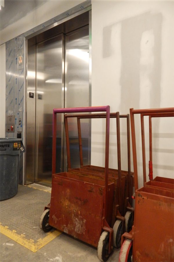 The third-floor door to the Bonney Center elevator. The red carts carry metal weights and will be used to test the elevator under load. (Doug Hubley/Bates College)