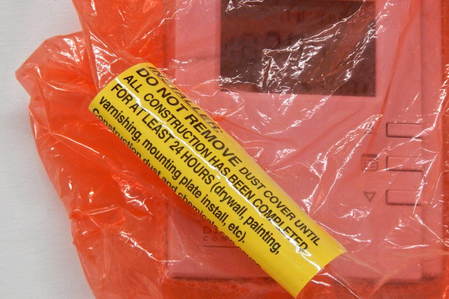 This label warns against removing a thermostat's orange protective cover before dust and fumes from construction work have settled once and for all. Such precautions are evident throughout the Bonney Center, from temporary filters on air intakes to similar protective films on a wide range of equipment. (Doug Hubley/Bates College)