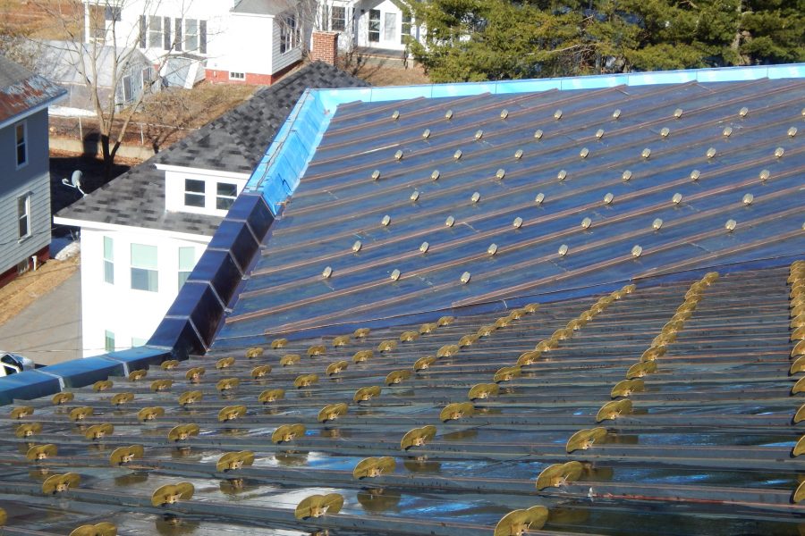 This view of the Bonney Center's south roof shows the ContinentalBronze panels, brass snow guards, and at left center, a rain gutter whose gray metal cladding is still incomplete. The nearest white house is the Health Services center. (Doug Hubley/Bates College)