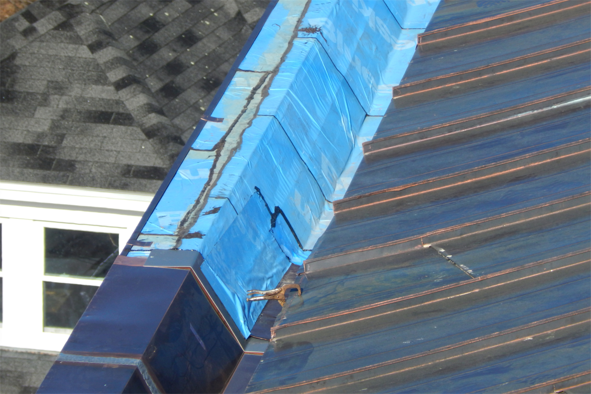 The light-blue section of this Bonney Center stormwater gutter still needfs its final metal covering. Note the  clamp on one of the flat panels. At left is the college health center. (Doug Hubley/Bates College)