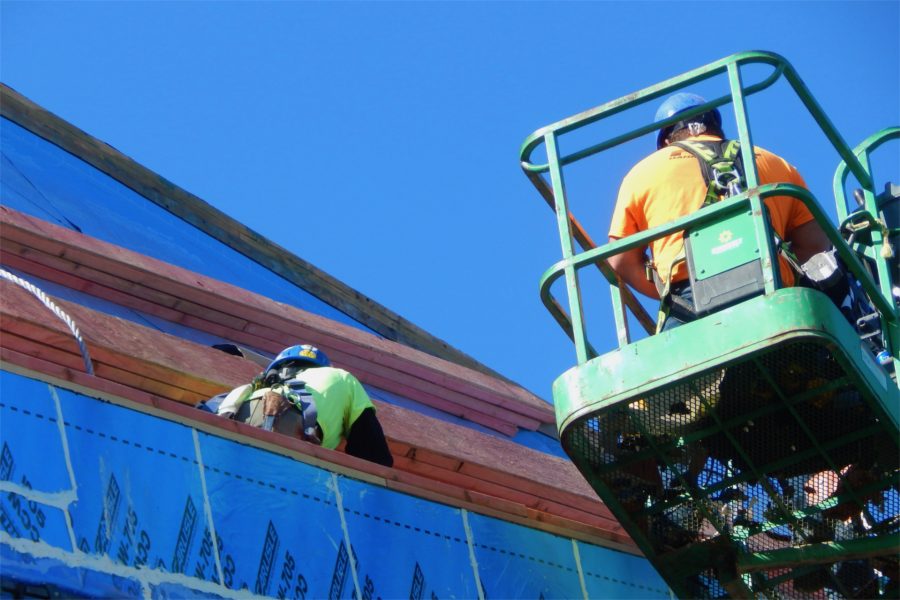 Roofers for Hahnel Bros. at work on the Campus Avenue side of the Bonney Science Center. The man at left is standing in a channel that will serve as a stormwater gutter. (Doug Hubley/Bates College)