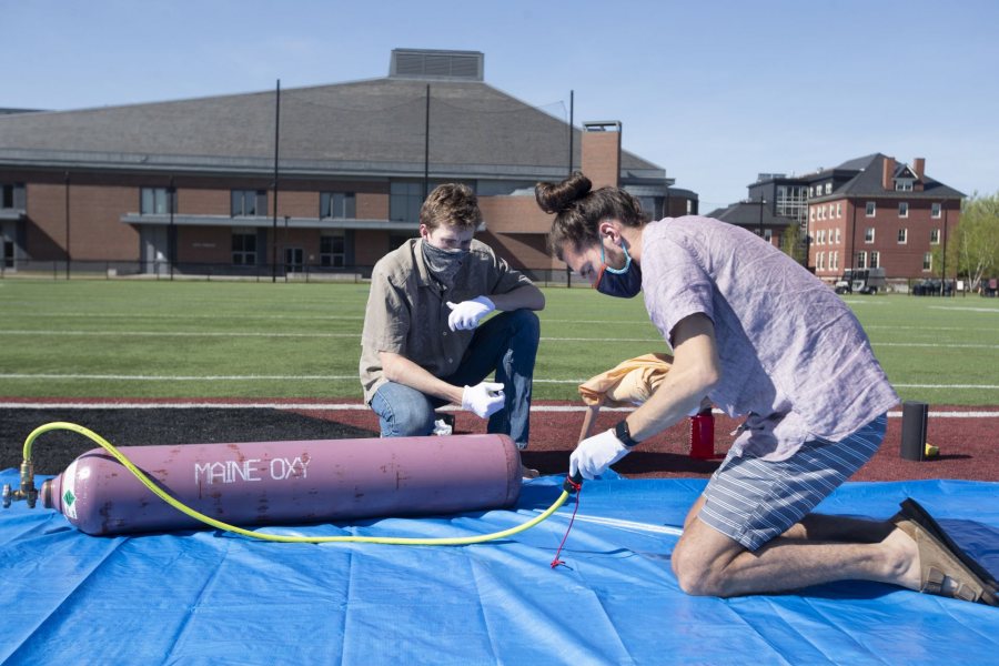 Barker and Jackson Donahue ‘22 of Princeton, N.J., prepare the connection to deliver helium gas to the balloon. (Phyllis Graber Jensen/Bates College)