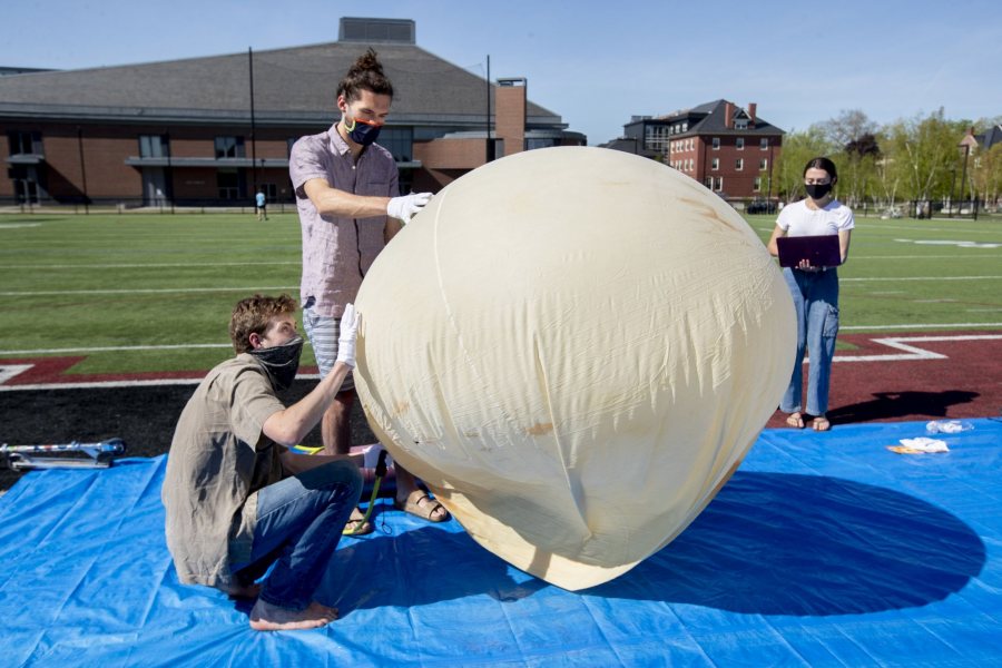 From left, Donahue, Barker, and Tara Ellard '22 of Brewster, Mass., assess the balloon as it’s being filled with helium gas. (Phyllis Graber Jensen/Bates College)