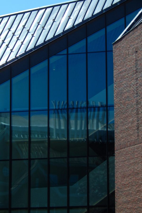 Carnegie Science Hall's rooftop exhaust stacks are reflected in the Bonney Center's Monumental Stair curtain wall. (Doug Hubley/Bates College)