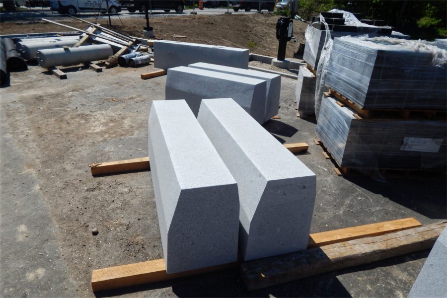 These concrete benches will be placed on the Bonney Science Center grounds. They resemble the benches found on Alumni Walk. At right are pallets of asphalt pavers; at rear is a charging station for electric vehicles. (Doug Hubley/Bates College)