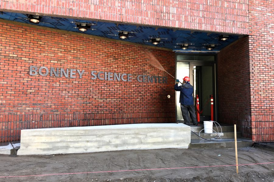 A worker power-washes brickwork at the Nichols Street entrance to the Bonney Science Center. (Jay Burns/Bates College)