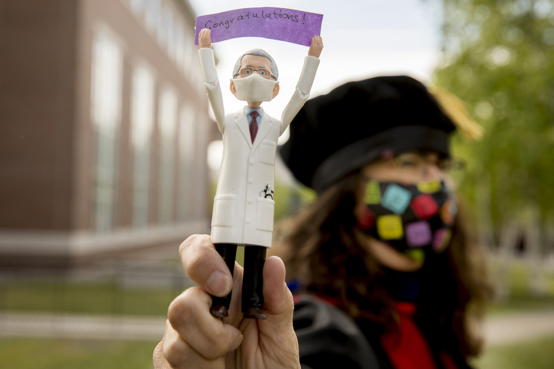 Professor of Chemistry and Biochemistry Paula Schlax displays a Dr. Anthony Fauci action figure holding the word "Congratulations" prior to the morning Commencement procession on May 27, 2021. Fauci received an honorary degree from Bates in 1993. (Phyllis Graber Jensen/Bates College)