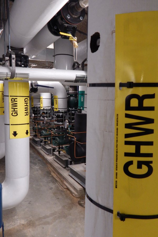 Water pumps, at center, and pipes in the Bonney Center penthouse. The liquids in this system are used to regulate interior air temperatures — "GHWR" stands for "glycol hot water." (Doug Hubley/Bates College)