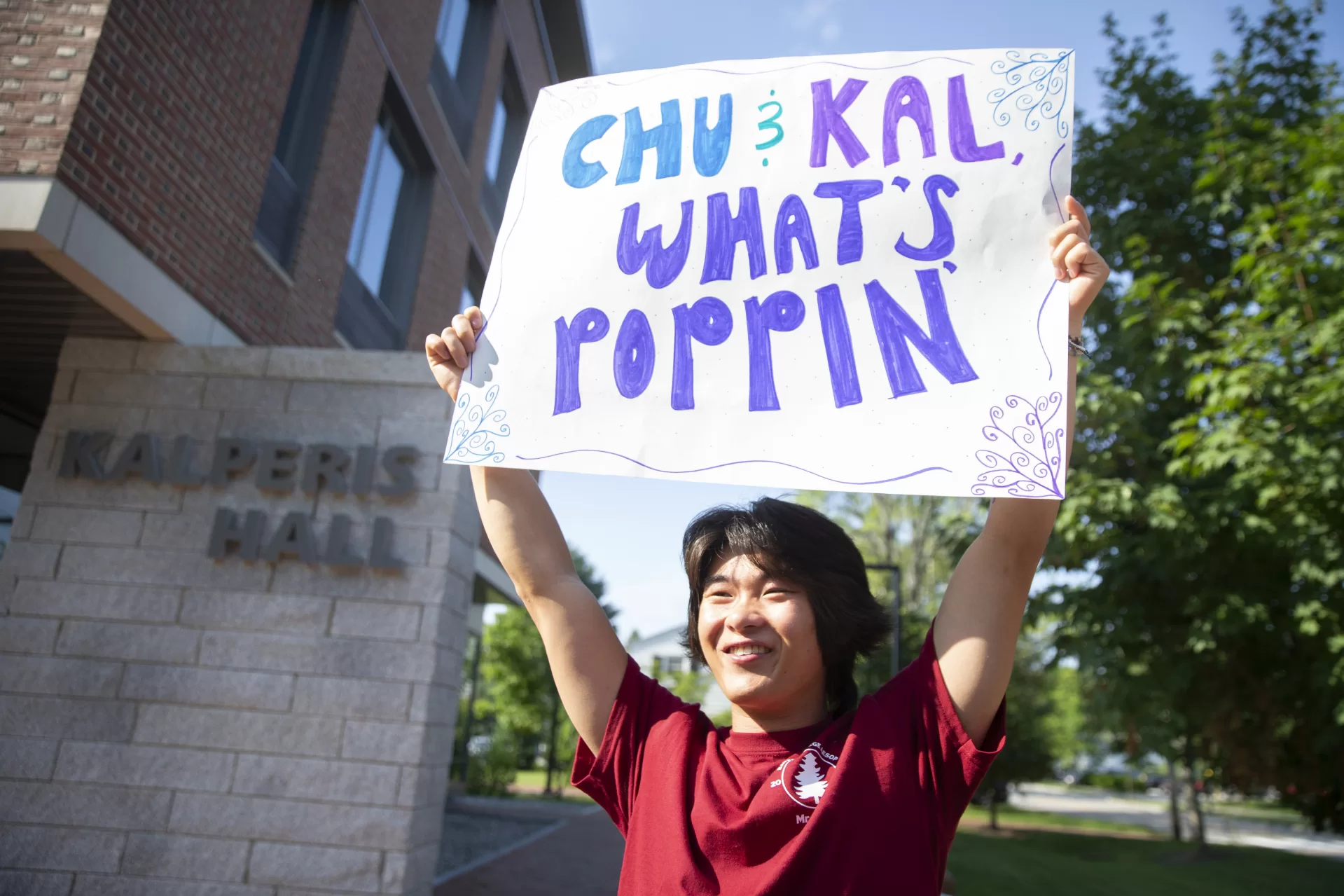 Nathan Huynh ’23 of San Diego, Calif., holds up a welcome sign for those moving into Kalperis Hall on Campus Avenue.