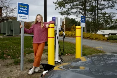Ecorep Tamsin Stringer ’22 of Bloomington, Ind., poses at the new electric charger stations behind Underhill in the Merrill Gym parking lot.“Underhill Electric Vehicle Chargers Project “Bates has installed other EV chargers in the past. This project will be different for three primary reasons. First, we have already received a grant from CMP for the make-ready infrastructure portion of the project, which has historically been the bulk of the expenses for EV charger installations. Secondly, this project will include installing level 2 chargers for the first time at Bates, which will allow for monetary collections for charging, tiered charging for different kinds of customers, and incentivize to move one’s car once it's fully charged. Finally, this project allows for future EV charger installations in the same location for much lower cost, because the make-ready infrastructure for more EV chargers will be easily accessible.