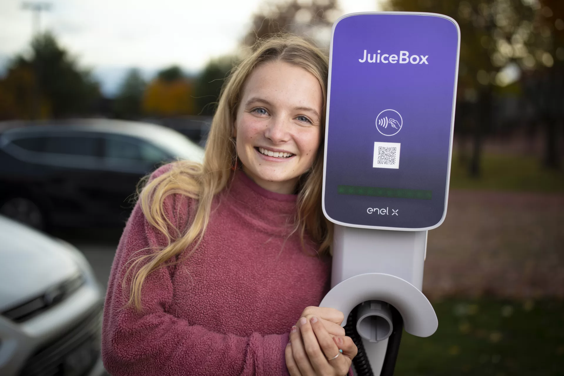 Ecorep Tamsin Stringer ’22 of Bloomington, Ind., poses at the new electric charger stations behind Underhill in the Merrill Gym parking lot.

“Underhill Electric Vehicle Chargers Project “
Bates has installed other EV chargers in the past. This project will be different for three primary reasons. First, we have already received a grant from CMP for the make-ready infrastructure portion of the project, which has historically been the bulk of the expenses for EV charger installations. Secondly, this project will include installing level 2 chargers for the first time at Bates, which will allow for monetary collections for charging, tiered charging for different kinds of customers, and incentivize to move one’s car once it's fully charged. Finally, this project allows for future EV charger installations in the same location for much lower cost, because the make-ready infrastructure for more EV chargers will be easily accessible.