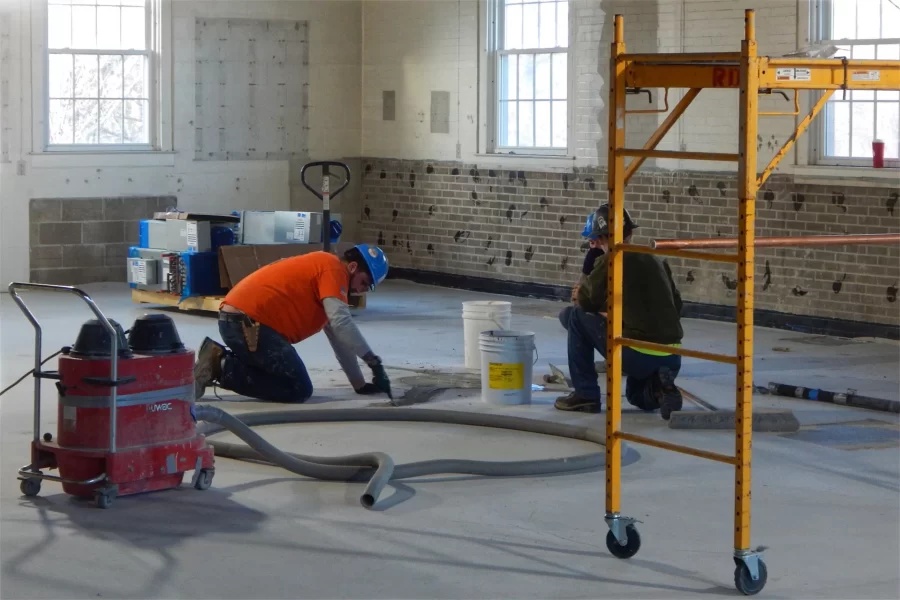 Flooring installers touch up a patch of self-leveling compound in a second-story Dana Chem classroom. (Doug Hubley/Bates College)